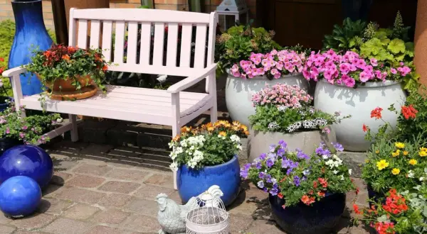 Kolorowe doniczki na balkon tworzą radosną kompozycję z różowymi petuniami, pomarańczowymi i białymi kwiatami.