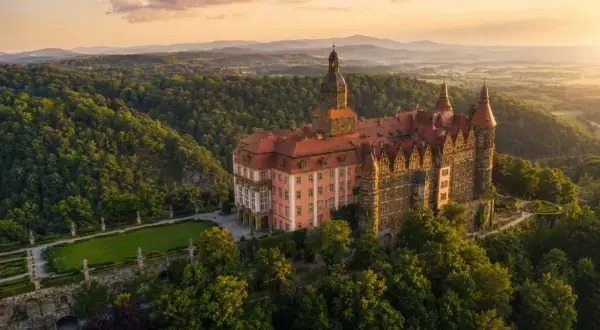 Zamek Książ, jedna z największych atrakcji Dolnego Śląska, w otoczeniu zielonych wzgórz o zachodzie słońca.