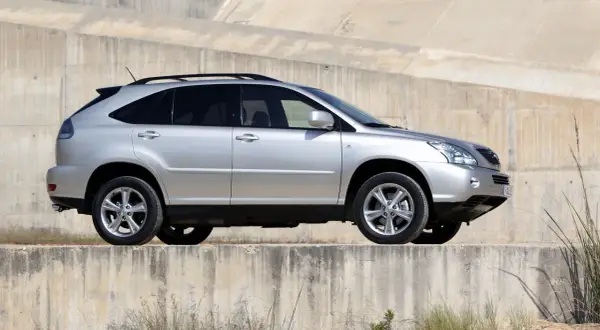 Srebrny Lexus RX 400h na tle betonowej ściany. Choć piękny, warto znać jego wady przed zakupem.