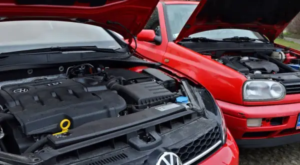 Dwa czerwone Volkswageny z otwartymi maskami. Widać silnik TDI, czyli silnik diesla, w nowszym modelu i starszy silnik w Golfie III.