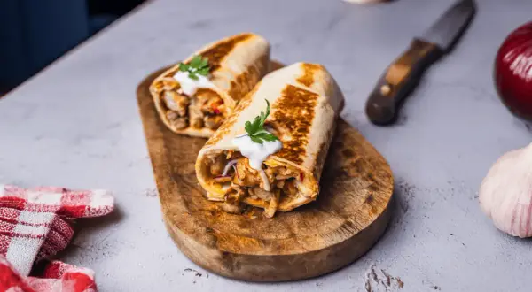 Dwa soczyste rolady z mięsem i warzywami, polane sosem, tworzą pyszny kebab w tortilli. Idealny na szybki posiłek.