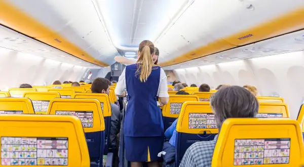 Wnętrze samolotu Ryanair, stewardessa obsługuje pasażerów. Słychać charakterystyczny buzz samolot.