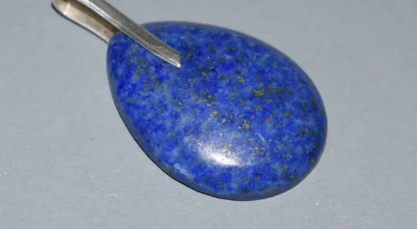Owalny wisiorek z lapis lazuli, kamienia o intensywnie niebieskim kolorze i złotych inkluzjach. Jego właściwości od wieków cenione są w ezoteryce.