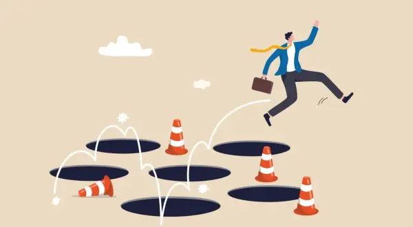 Un homme d'affaires saute par-dessus des trous, évitant les cônes de signalisation. Une métaphore visuelle pour surmonter les obstacles, comme un exemple d'arrêt de travail.