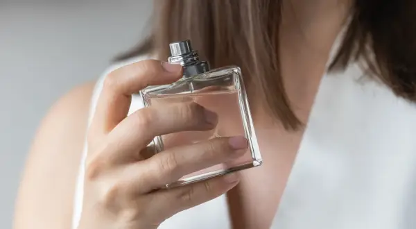 Kobieta testuje perfumy, szukając idealnego zapachu dla siebie. Elegancka buteleczka w dłoni.