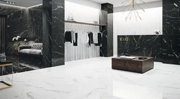 Elegancki butik z czarnymi ścianami w żyłach nero marquina i białymi podłogami. Wieszaki z ubraniami, kanapa i lada recepcyjna.
