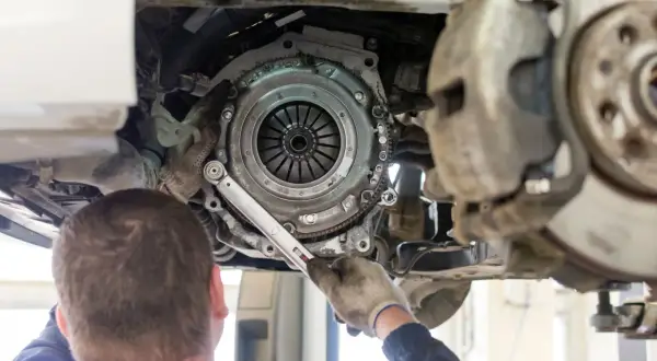Mechanik dokonuje wymiany sprzęgła w samochodzie, używając klucza dynamometrycznego do precyzyjnego dokręcenia śrub.