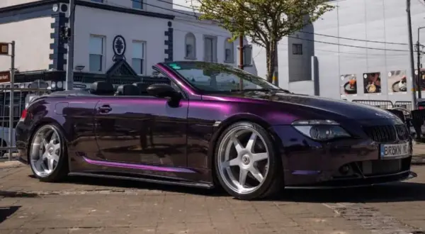Fioletowe BMW E64 kabriolet z chromowanymi felgami stoi na ulicy.