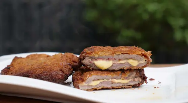 Zwei dampfende Cordon Bleu auf einem Teller, das Fleisch ist saftig, der Käse schmilzt.