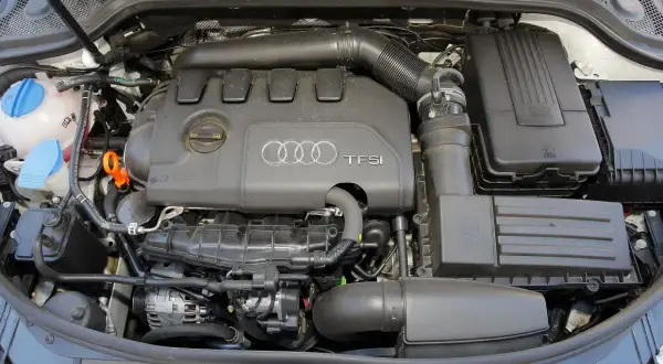 Silnik TFSI w Audi 8P. Widoczne elementy układu dolotowego, zbiornik płynu chłodniczego i alternator.