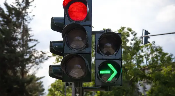 Sygnalizacja świetlna z czerwonym światłem na górze i zieloną strzałką po prawej. Czas jechać!