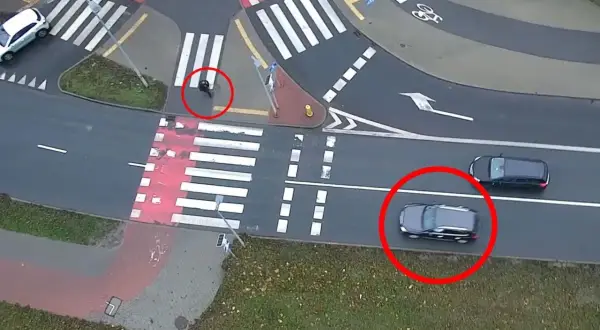 Osoba na przejściu dla pieszych, samochody czekają.