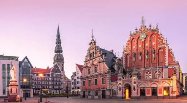 Ratusz i Dom Bractwa Czarnogłowych w Rydze, z wieżą kościoła św. Piotra w tle, o wschodzie słońca.