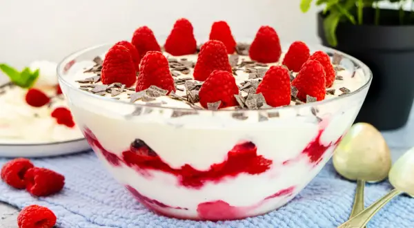 Himbeer Baiser Nachtisch in einer Glasschüssel, garniert mit frischen Himbeeren und Schokostückchen. Ein Traum!