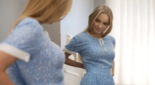 Młoda kobieta w kwiecistej sukience, uosobienie stylu lat 30. moda, przymierza strój przed lustrem.