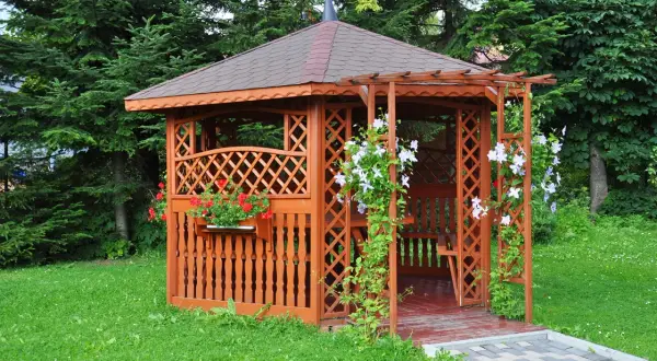 Urocza altana na działce ROD, otoczona zielenią, z kwitnącymi pnączami i pelargoniami. Idealne miejsce na relaks.
