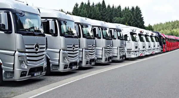 Rangée de camions Mercedes-Benz argentés et blancs, prêts pour le transport. La réglementation stationnement poids lourds est respectée.