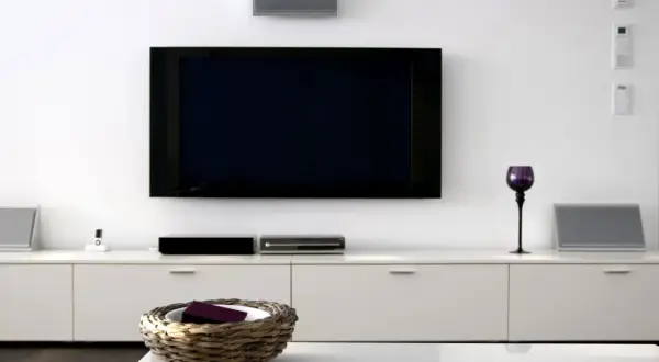 Nowoczesny salon z dużym telewizorem na ścianie, białymi meblami i dekoracjami.
