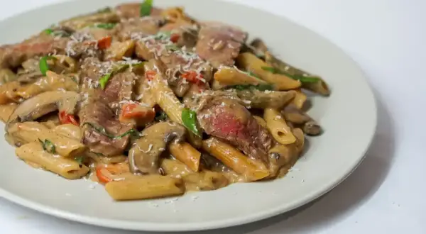 Penne z kawałkami soczystej wołowiny w kremowym sosie z pieczarkami i pomidorkami. Idealne, co w piątek na obiad zamiast ryby.