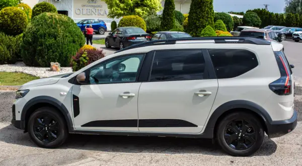 Jasnoszary Dacia Jogger na parkingu. Zastanawiasz się nad jego spalaniem? Ten rodzinny samochód oferuje przestronność i praktyczność.