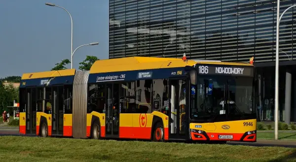 Autobus 186 linii Nowodwory w Warszawie, ekologiczny, zasilany CNG, stoi na tle nowoczesnego budynku.