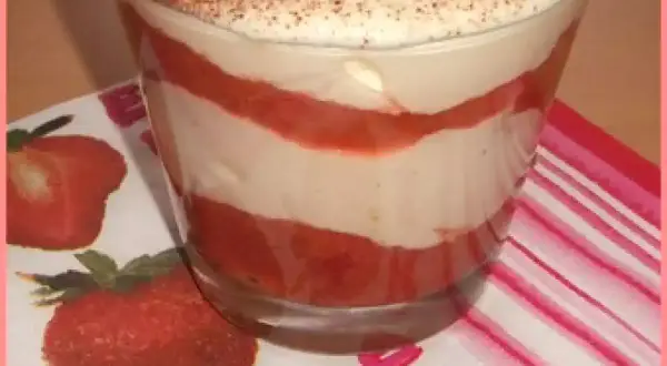 Un délicieux tiramisu rhubarbe fraise, superposé en couches dans un verre, garni de fraises et de cacao.