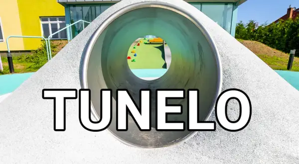 Tunel na placu zabaw z widokiem na kolorowe elementy i budynek.