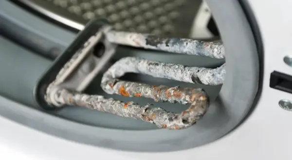 Stark verkalkter Heizstab einer Waschmaschine. Kalkablagerungen beeinträchtigen die Leistung und Lebensdauer. Zeit, die Waschmaschine zu entkalken!