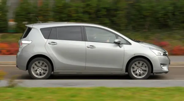 Srebrna Toyota Verso w ruchu. Zastanawiasz się nad jej wadami i zaletami? Ten rodzinny minivan oferuje przestronne wnętrze i komfort.