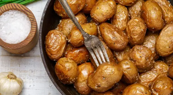 Pommes de terre grenaille dorées et croustillantes, tout juste sorties de l'airfryer. Une fourchette est plantée dans ce délice salé.