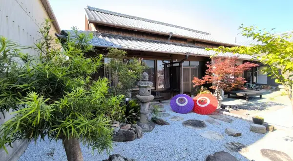 Tradycyjny dom na wyspie Japonii z Kagawa, z kamiennym ogrodem, parasolami i jesiennym drzewem klonowym.