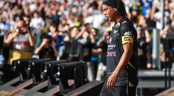 Ronaldinho w czarnej koszulce z żółtym opaską na ramieniu, z tłumem w tle.