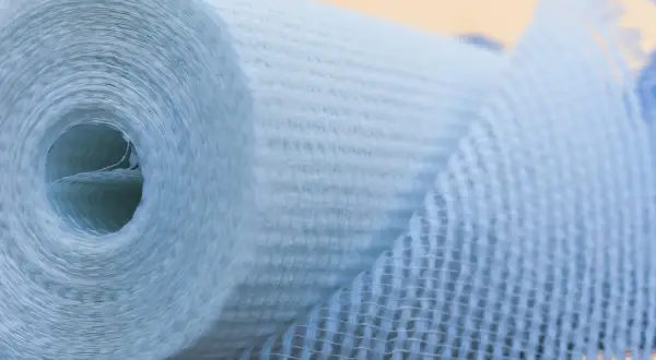 Rolle aus Glasfasergewebe, bereit zum Glasfasertapete kleben. Das Material ist hellblau und hat eine feine Netzstruktur.