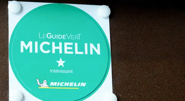Adesivo verde Michelin con una stella, che indica un riconoscimento "Interessante" per un ristorante.