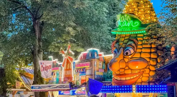 Buntes Volksfest mit Maiskolben-Figur und Buden. Das bergkirchweih erlangen programm lockt mit Leckereien.