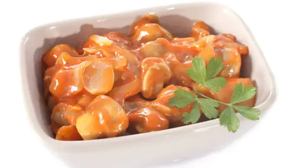 Un plat de champignons à la grecque, tendres et savoureux, baignant dans une sauce tomate onctueuse, garni d'une touche de persil frais.