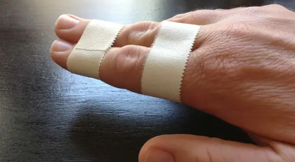Zwei Finger sind mit Pflaster verbunden, um sie zu stabilisieren. Das Finger tapen hilft bei der Heilung.