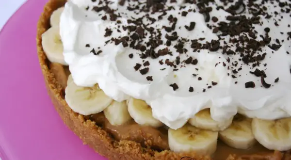 En krämig banoffee paj med lager av banan, kolasås och vispad grädde, toppad med chokladströssel.