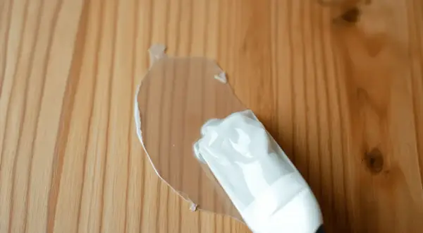 Une nouvelle lasure transparente recouvre une ancienne lasure sur un bois clair.