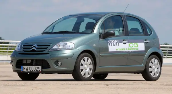 Zielony Citroen C3 z naklejką "Stop & Start" i informacją "W trosce o środowisko". Widać przednie żarówki.