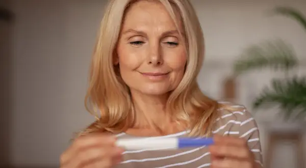 Bea Szenfeld, med ett leende, håller ett graviditetstest.