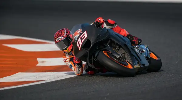 Piloto de MotoGP inclinado en curva, con su moto negra y naranja. La potencia de cuántos caballos tiene una MotoGP es asombrosa.