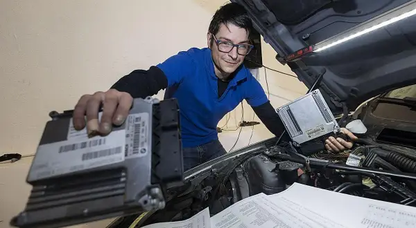 Técnico con gafas revisa unidades de control para modificaciones coche.