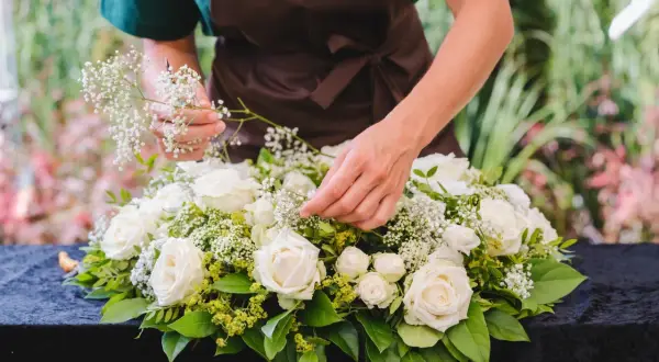 Tworzenie wiązanki na cmentarz: białe róże, gipsówka i zieleń tworzą elegancką kompozycję.