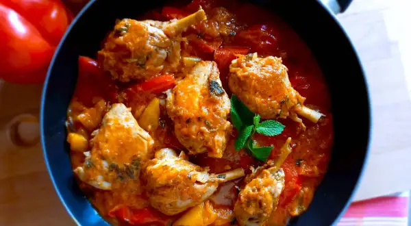 Un saporito pollo con peperoni in padella, con pezzi di pollo succulenti immersi in una ricca salsa rossa e verdure colorate.