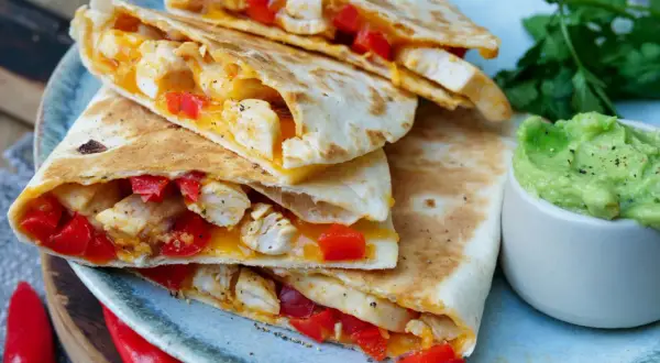 Leckeres Quesadillas Rezept: goldbraune Tortillas gefüllt mit Hähnchen, roter Paprika und geschmolzenem Käse, serviert mit Guacamole.