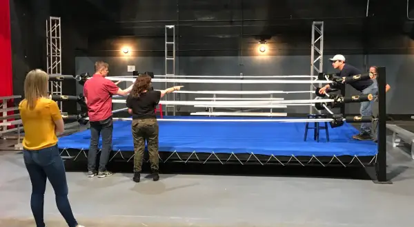 A group discusses a 12 week boxing training program around a wrestling ring.