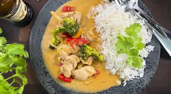 En smakrik thaigryta med kyckling, broccoli och paprika i en krämig sås, serverad med fluffigt ris.