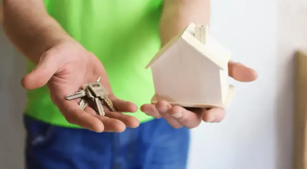 Ręce trzymają klucze i model domu. Zastanawiasz się, na co zwrócić uwagę przy umowie najmu?
