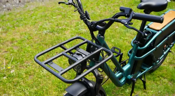 Zielony rower elektryczny dla seniora z dużą platformą bagażową z przodu i wygodnym siodełkiem. Idealny na zakupy i wycieczki.
